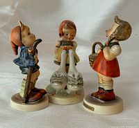Front oblique view of all three Goebel Hummel figurines standing together