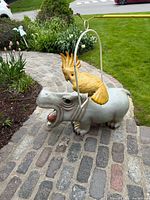Hippopotamus figure outdoors with cockatoo on swing for scale