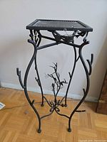 Full view of wrought iron plant stand showing square top and decorative legs