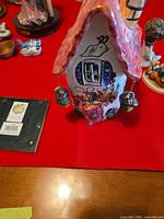 Front view of hand-painted ceramic fairy cottage showing roof, windows, door and hanging lanterns