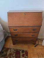 Front view of brown wood veneer secretary desk showing drop-front, drawers and hardware