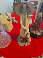 Front view of elongated ceramic angel-woman figurine with hat and child at base