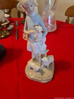 Front view of porcelain figurine showing girl, lamb, and two sheep