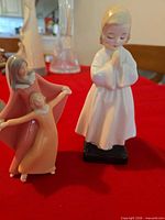 Mother with child figurine beside praying child figurine on red cloth