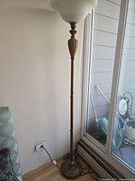 Full view of brass floor lamp beside window