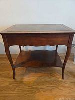 Full view of dark walnut veneer end table showing leather inset top, cabriole legs, lower shelf