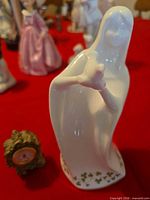 porcelain figurine next to miniature clock on red background
