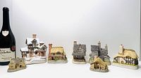 Group shot of all seven cottages next to wine bottle for scale