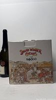 Front of Enesco David Winter Cottages box beside scale bottle