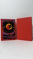 Book standing beside slipcase showing front cover artwork and slipcase colour