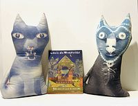 Front view of both cat pillows with closed book between