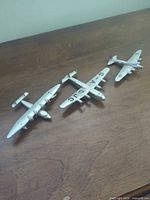 Three silver diecast airplanes on wooden surface