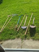 All seven long-handled garden tools lined on grass