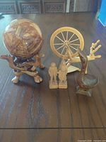 Group view: wooden sphere on stand, mini spinning wheel, two small carved figurines, carved boat-shaped vase