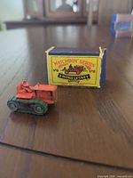 Die-cast tractor next to original Matchbox box front view