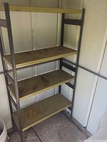 Full view of metal frame shelving unit with four green shelves inside shed