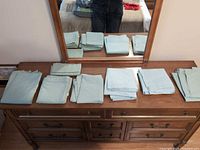 folded mint green queen sheets and pillowcases on dresser