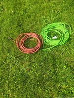 Red and green outdoor extension cords coiled on grass