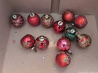 Box containing 12 red and green glass ornaments with gold trim