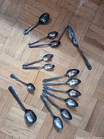 Mixed group of silver-plated spoons and butter spreader arranged on floor