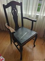 Full view of dark brown wooden armchair with black vinyl seat