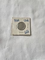 Front view of holder showing obverse of 1934 nickel and handwritten label