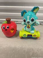 Front view of teal puppy on scooter and red apple shape sorter