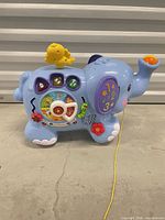 Left side view of blue VTech activity elephant showing activity wheel, numeric buttons, bird figure and pull string
