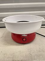 Cotton candy maker assembled showing red base, white bowl, on-off switch and power cord