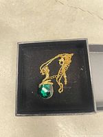 Necklace in box showing green crystal pendant and chain