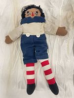 Full view of cloth rag doll lying flat showing entire outfit and striped legs