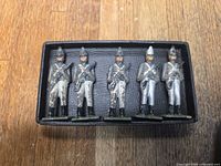 Front view of five cast metal toy soldiers in box