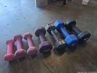 Seven dumbbells lined up left to right showing size and colour range
