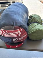 Coleman 50°F sleeping bag next to rolled green air mattress