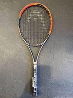 Front view of the Head tennis racket showing frame, strings, and plastic-wrapped grip