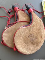 Two suede leather canteens with red trim and cords