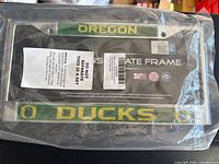 Front view of sealed University of Oregon Ducks license plate frame showing full text and packaging