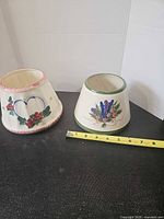 Both ceramic candle toppers beside measuring tape showing diameter