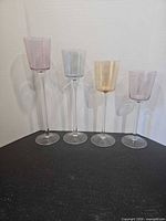 Front view showing four coloured glass stemmed candle holders