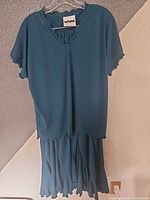 Front view of teal Mondiki top and skirt hanging