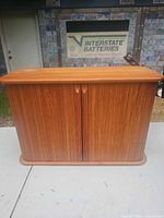 Front view of closed cabinet showing wood veneer tambour doors and rounded edges