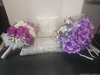 Group shot of both bouquets, packaged ring pillow and sequined tablecloth