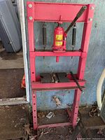 Full view of red steel shop press frame with bottle jack, handle and V-blocks