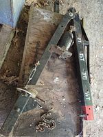 Overall view of engine hoist boom with jack, chains and pins lying on wood surface