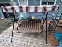 Front view of swing showing striped canopy, cushion, metal frame