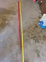 Full view of red pry bar beside measuring tape showing ~96 in length