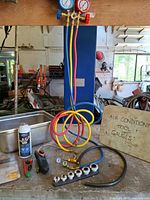 Overall lot showing manifold, hoses, refrigerant can, leak detector, fittings