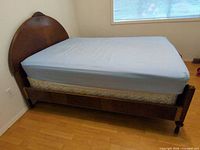 Side view of assembled bed showing mattress on frame, wooden side rail and legs