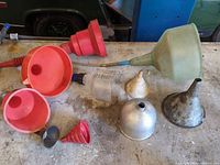 Workbench view showing eight assorted funnels of plastic and metal