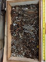 Top view of mixed bolts, nuts, washers and screws in wood box